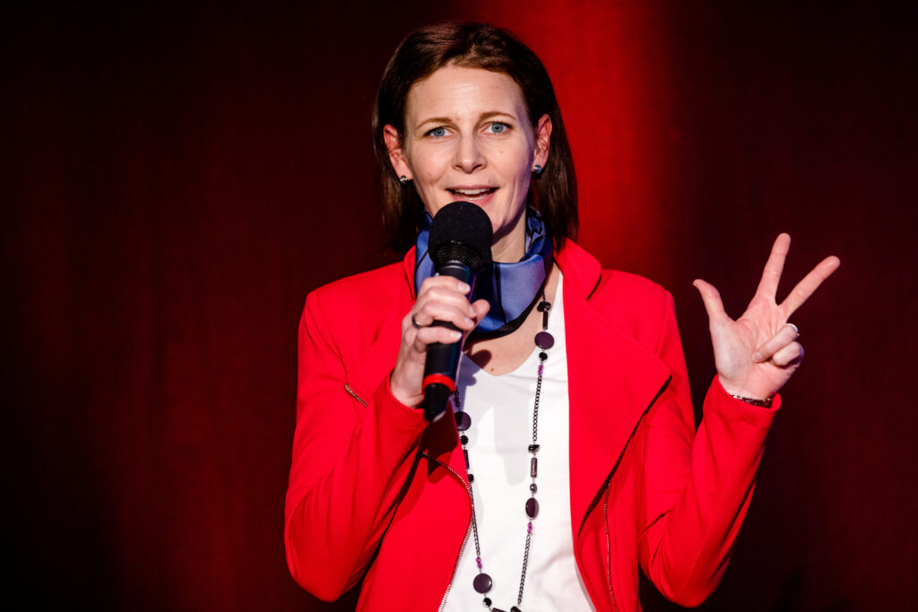 Kirsten Wunderle im roten Blazer mit Handmikrofon