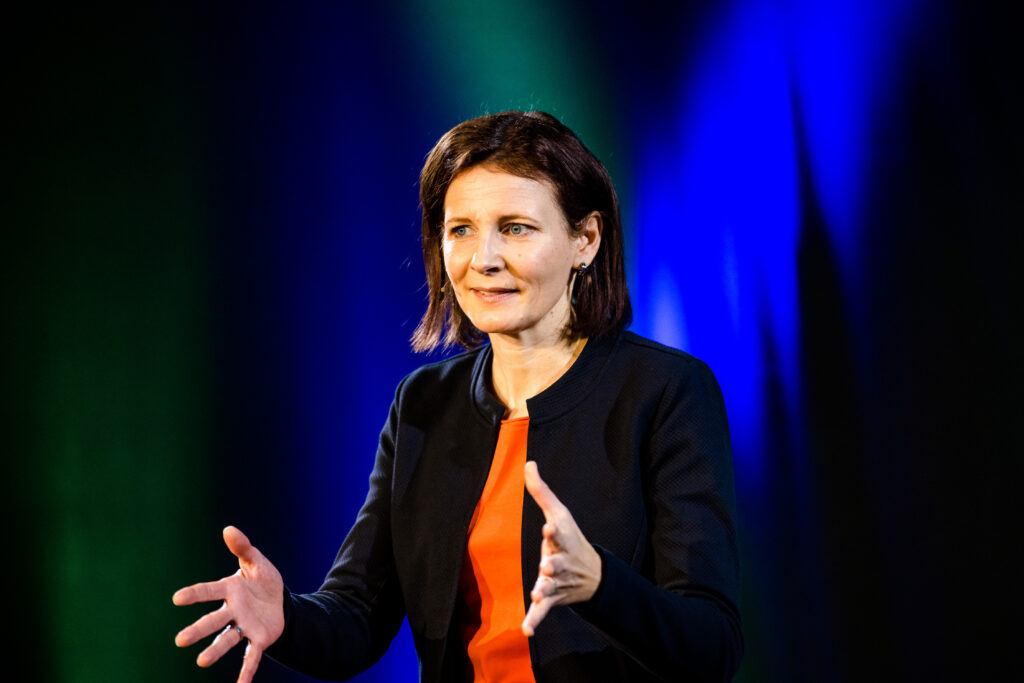 Kirsten Wunderle spricht vor blau-grünem Bühnenlicht
