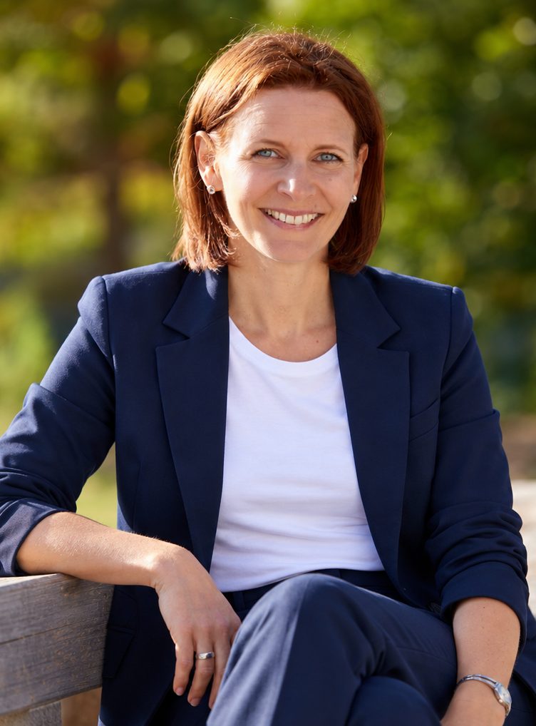 Kirsten Wunderle sitzt lächelnd auf einer Bank